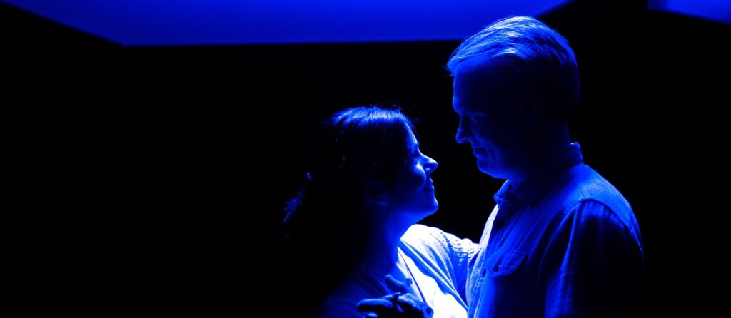 A man and a woman in blue light, in dance position